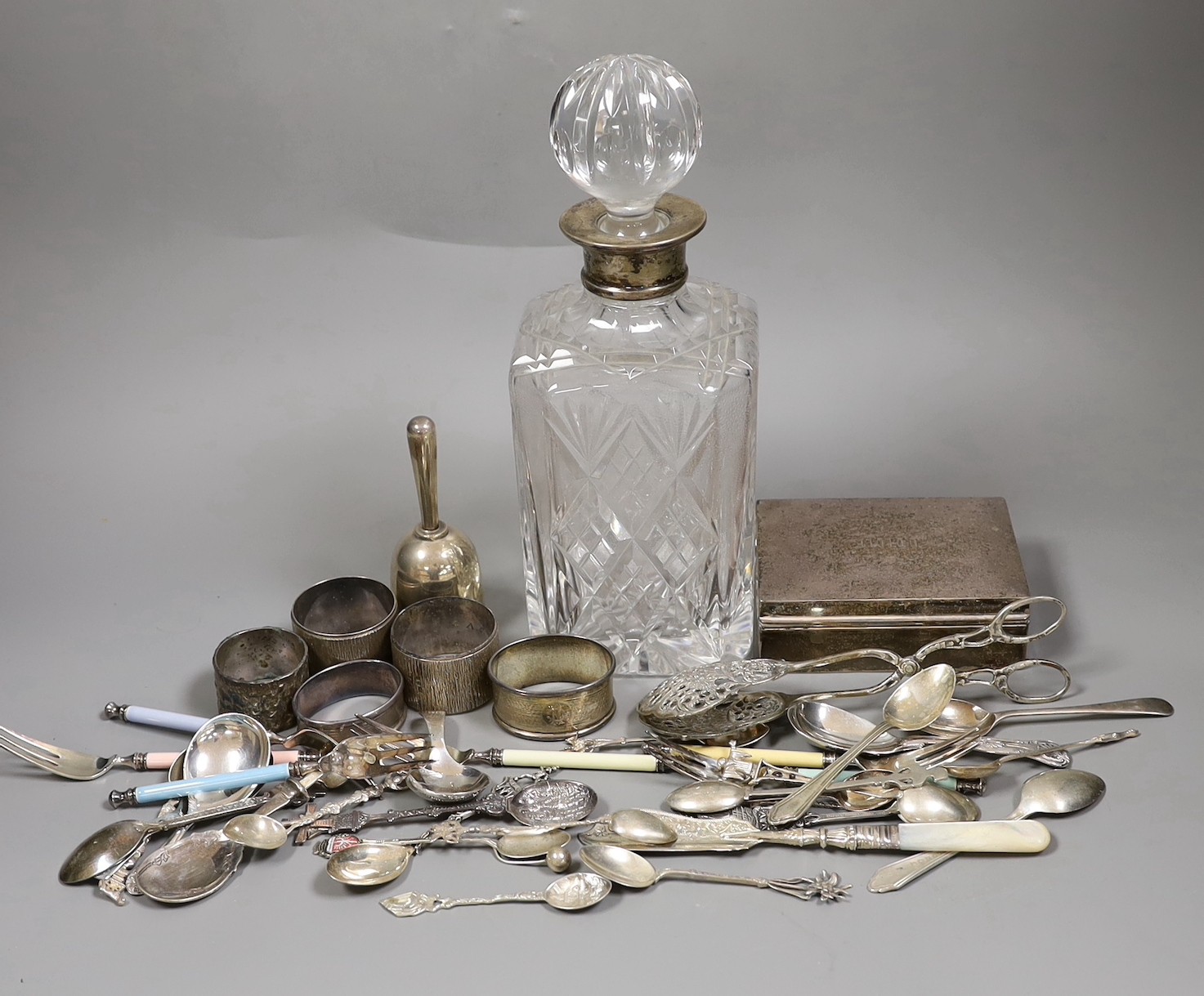 Mixed silver items etc. including a modern silver collared glass decanter, cigarette box, 800 standard white metal cake tongs, a white metal hand bell(lacking clapper), six plated Noritake tea forks, assorted minor silve